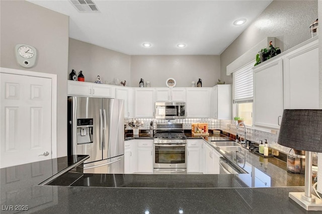 kitchen with visible vents, dark countertops, tasteful backsplash, a sink, and stainless steel appliances