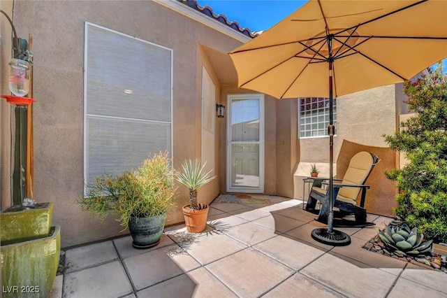 view of exterior entry featuring stucco siding and a patio area