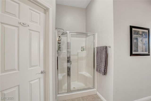 bathroom featuring baseboards, a shower stall, and tile patterned flooring