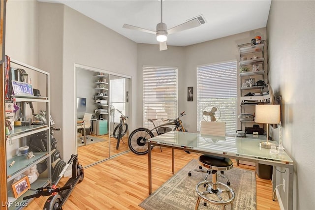 office space with a ceiling fan, visible vents, and wood finished floors