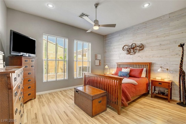bedroom featuring visible vents, an accent wall, light wood-style floors, wooden walls, and recessed lighting
