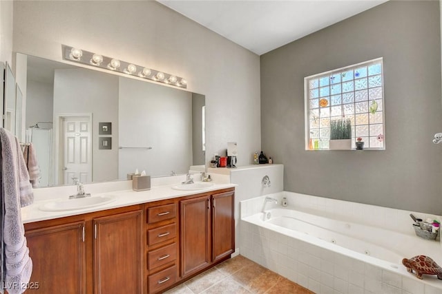bathroom with double vanity, a whirlpool tub, tile patterned floors, and a sink