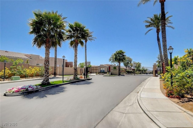 view of street featuring street lighting, a gate, sidewalks, and curbs
