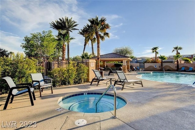 pool with a hot tub, a patio, a gazebo, and fence
