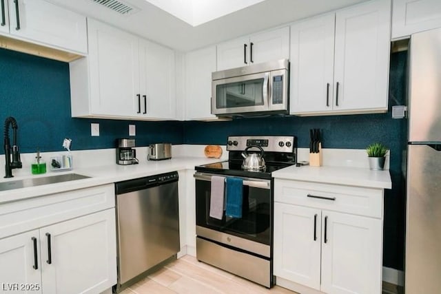 3789 Heritage Ave, Las Vegas, NV 89121 - kitchen featuring stainless steel appliances, white cabinetry, light countertops, a sink, and light wood-style flooring