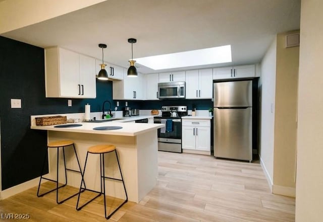 3789 Heritage Ave, Las Vegas, NV 89121 - kitchen featuring appliances with stainless steel finishes, a peninsula, a sink, white cabinetry, and light wood finished floors
