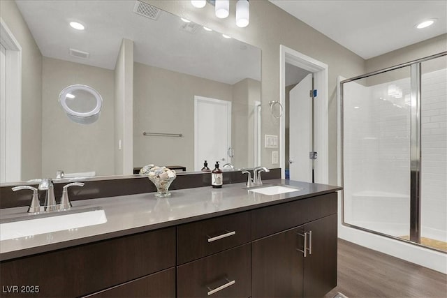 full bath with a sink, a shower stall, wood finished floors, and visible vents