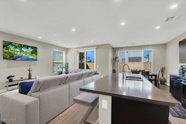 living area with light wood-style floors, baseboards, recessed lighting, and visible vents