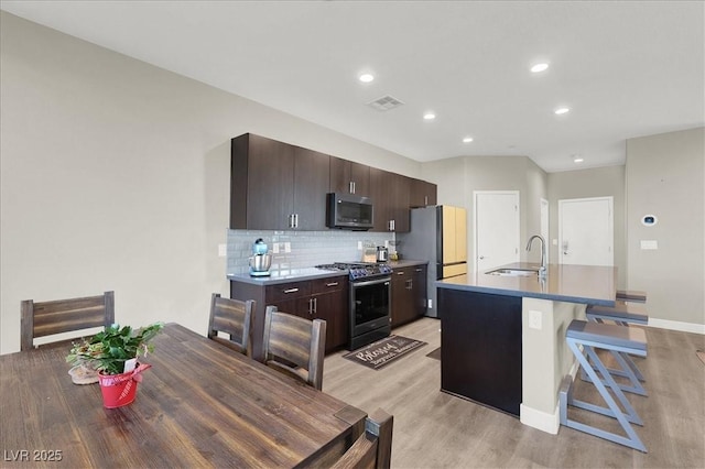 kitchen with visible vents, light wood-style floors, appliances with stainless steel finishes, and a center island with sink