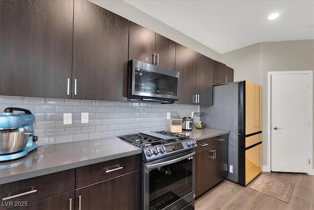 kitchen featuring dark brown cabinetry, light countertops, tasteful backsplash, light wood finished floors, and stainless steel appliances