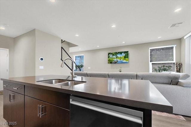 kitchen with open floor plan, a sink, dishwasher, and dark brown cabinets