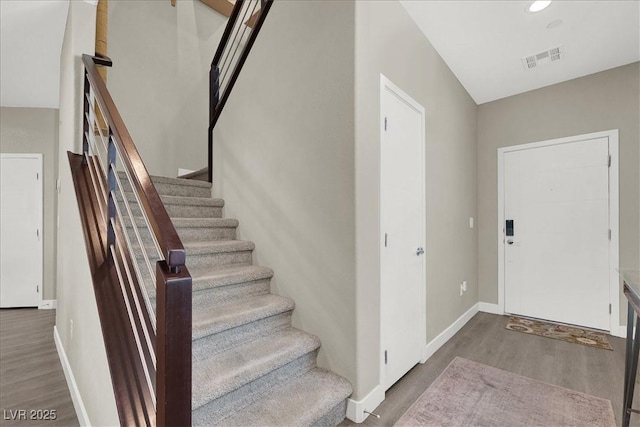stairs with baseboards, visible vents, and wood finished floors