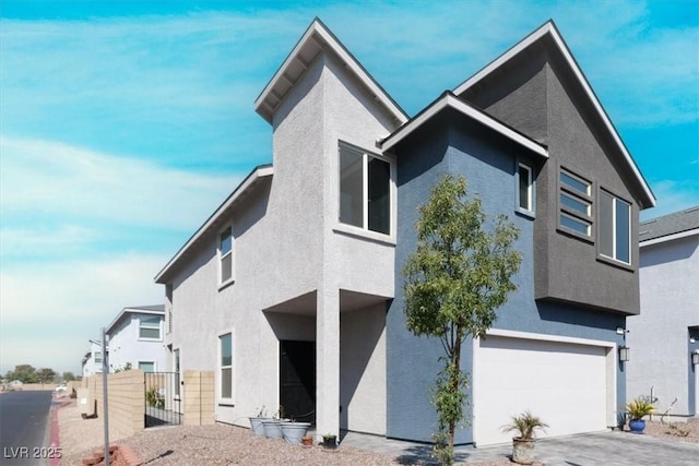 view of front of house featuring stucco siding, fence, and a garage