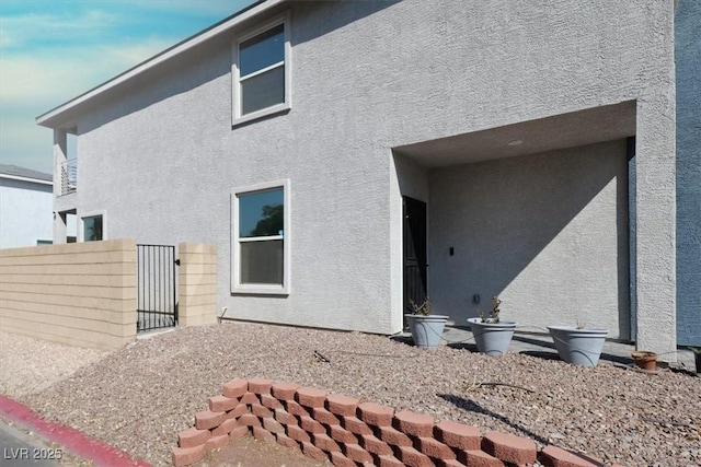back of property featuring fence, a gate, and stucco siding