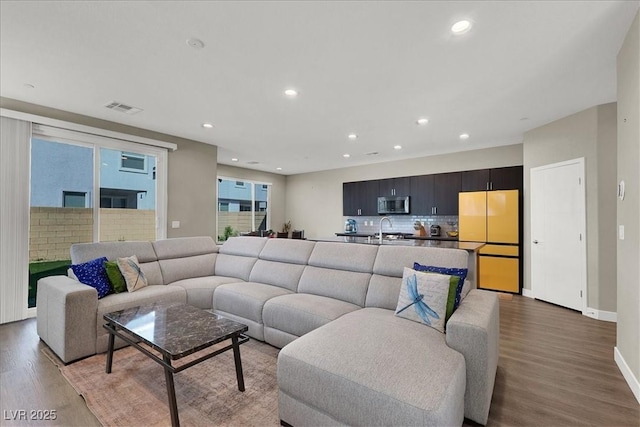 living area with visible vents, recessed lighting, and wood finished floors