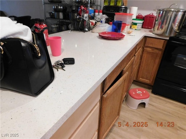 kitchen with light countertops, light wood-type flooring, brown cabinets, and range