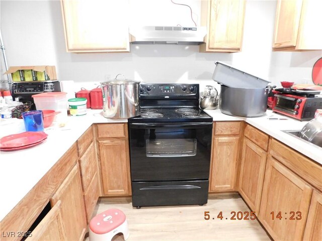 kitchen with light wood-style floors, light countertops, under cabinet range hood, and black / electric stove