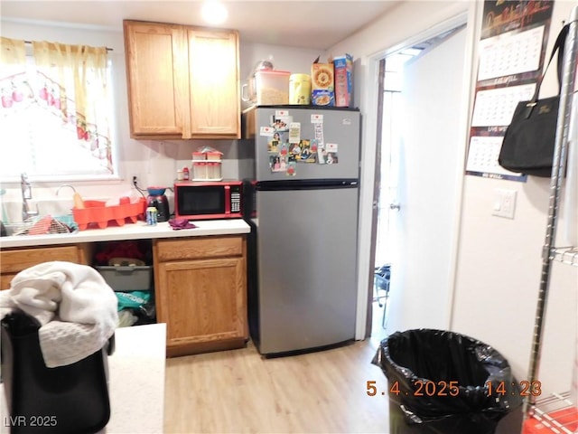 kitchen with light wood-style floors, light countertops, and freestanding refrigerator