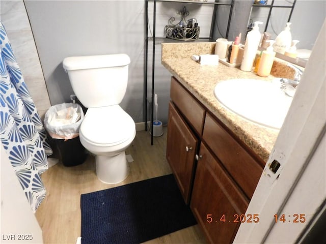 bathroom featuring vanity, wood finished floors, toilet, and curtained shower