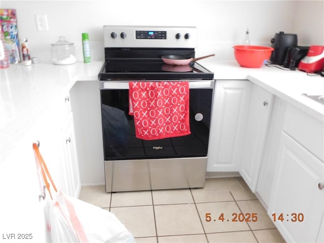kitchen featuring white cabinets, stainless steel electric stove, light tile patterned floors, and light countertops