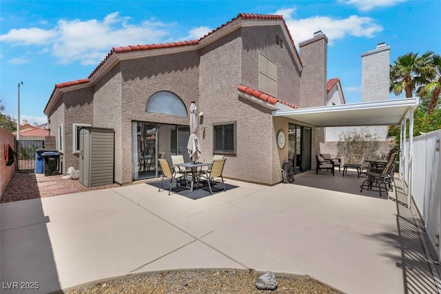 rear view of property with a tiled roof, a fenced backyard, a patio area, and stucco siding