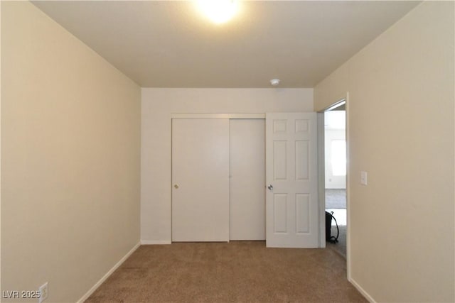 unfurnished bedroom featuring baseboards, carpet, and a closet
