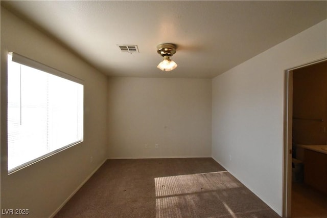 spare room with baseboards, carpet, and visible vents