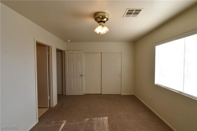 unfurnished bedroom featuring visible vents, carpet, baseboards, and a closet