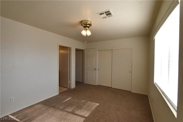 unfurnished bedroom featuring a closet, carpet flooring, and visible vents