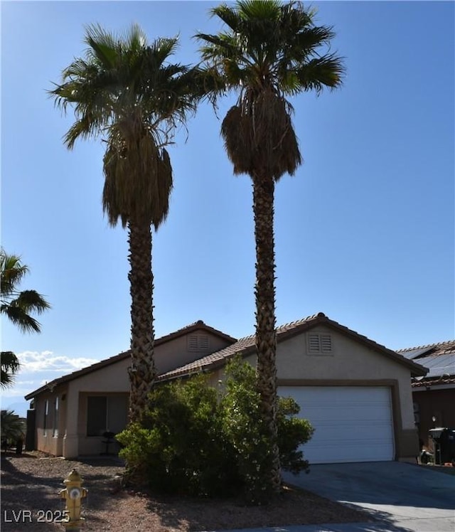 exterior space with a tiled roof, a garage, stucco siding, and driveway