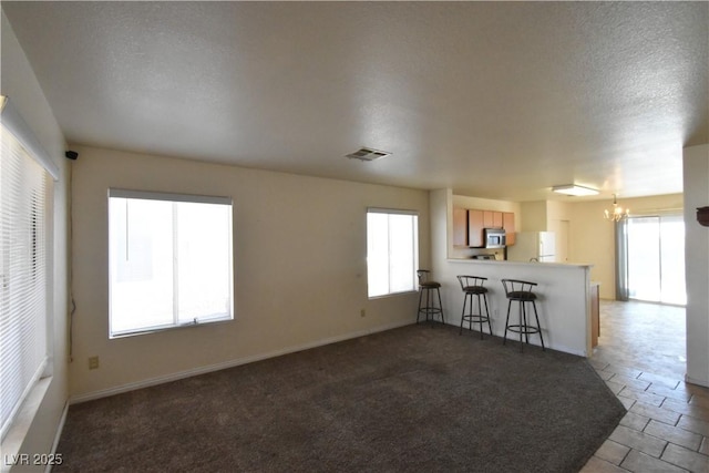unfurnished living room featuring a chandelier, baseboards, visible vents, and a healthy amount of sunlight