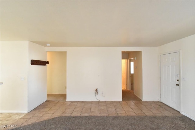 carpeted empty room with baseboards and tile patterned flooring
