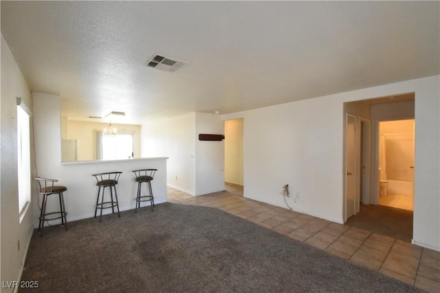 carpeted living room featuring visible vents, baseboards, and tile patterned floors