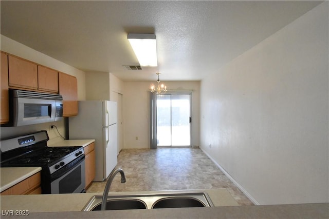 kitchen featuring visible vents, appliances with stainless steel finishes, a sink, light countertops, and an inviting chandelier