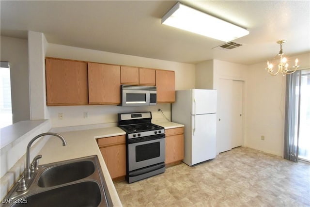 kitchen featuring visible vents, appliances with stainless steel finishes, a sink, light countertops, and a chandelier