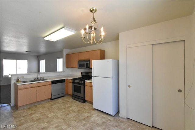 kitchen with pendant lighting, appliances with stainless steel finishes, a sink, light countertops, and a notable chandelier