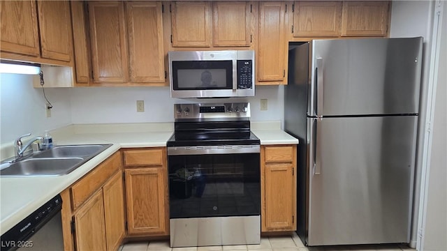 kitchen with light countertops, appliances with stainless steel finishes, brown cabinetry, and a sink