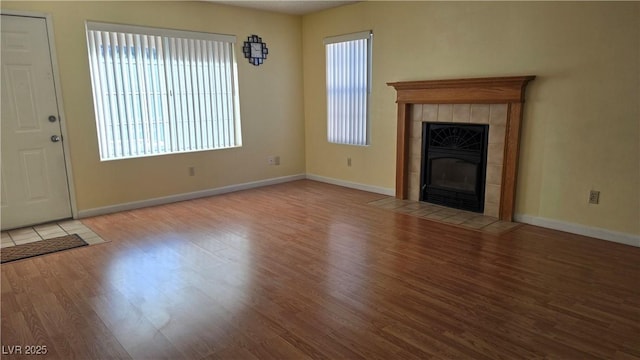 unfurnished living room featuring baseboards, wood finished floors, and a tile fireplace