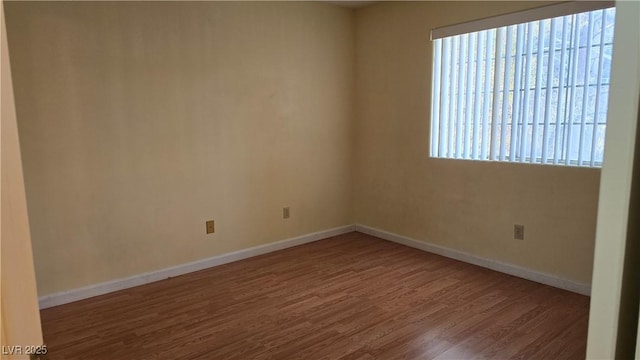unfurnished room with baseboards and wood finished floors