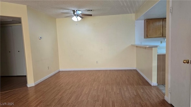interior space featuring a textured ceiling, ceiling fan, wood finished floors, and visible vents