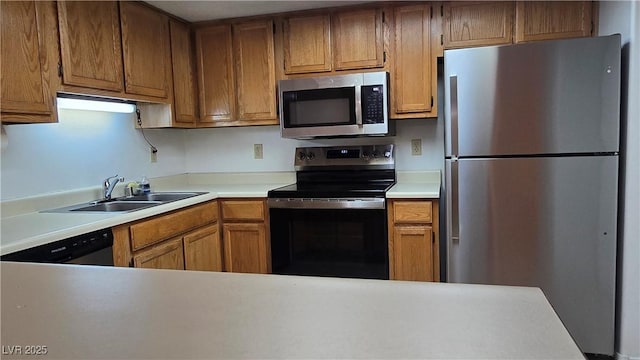 kitchen with brown cabinetry, a sink, appliances with stainless steel finishes, and light countertops