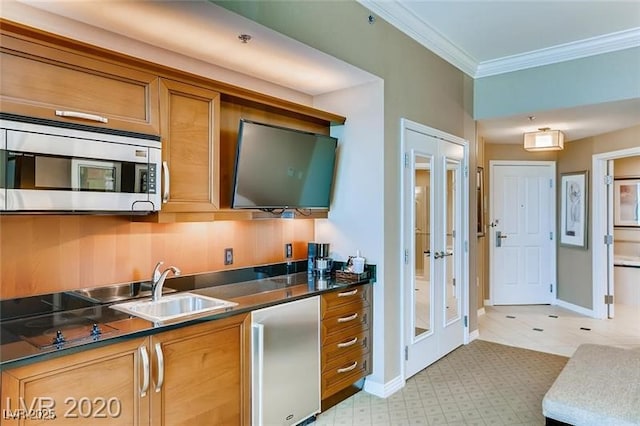 kitchen with crown molding, appliances with stainless steel finishes, brown cabinets, a sink, and baseboards