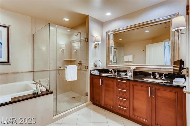 bathroom with double vanity, a bath, tile patterned flooring, a stall shower, and a sink