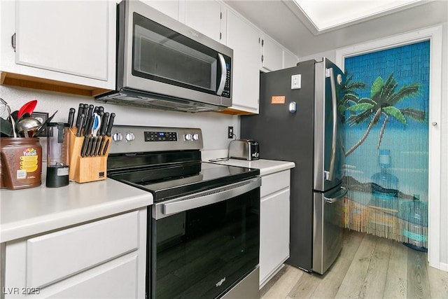 kitchen with light countertops, stainless steel appliances, white cabinetry, and light wood finished floors