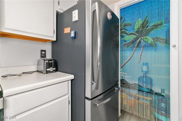 kitchen featuring freestanding refrigerator, white cabinets, and light countertops