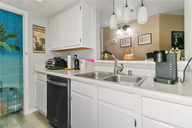 kitchen featuring light countertops, white cabinets, a sink, light wood finished floors, and dishwasher
