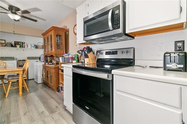 kitchen featuring light countertops, washing machine and clothes dryer, a ceiling fan, light wood-style flooring, and appliances with stainless steel finishes