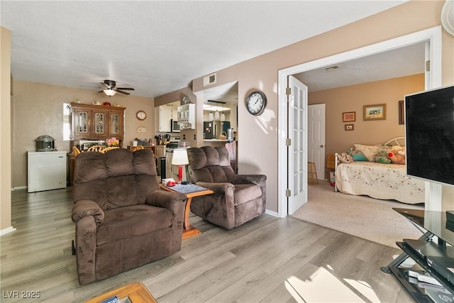 living area with light wood-style floors, baseboards, ceiling fan, and visible vents