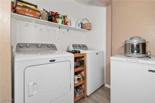 laundry room with laundry area, washing machine and dryer, and light wood finished floors
