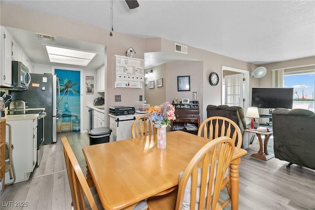 dining space with light wood-style floors, a ceiling fan, and visible vents